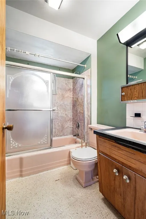 Bathroom with vanity, bath / shower combo with glass door, and backsplash