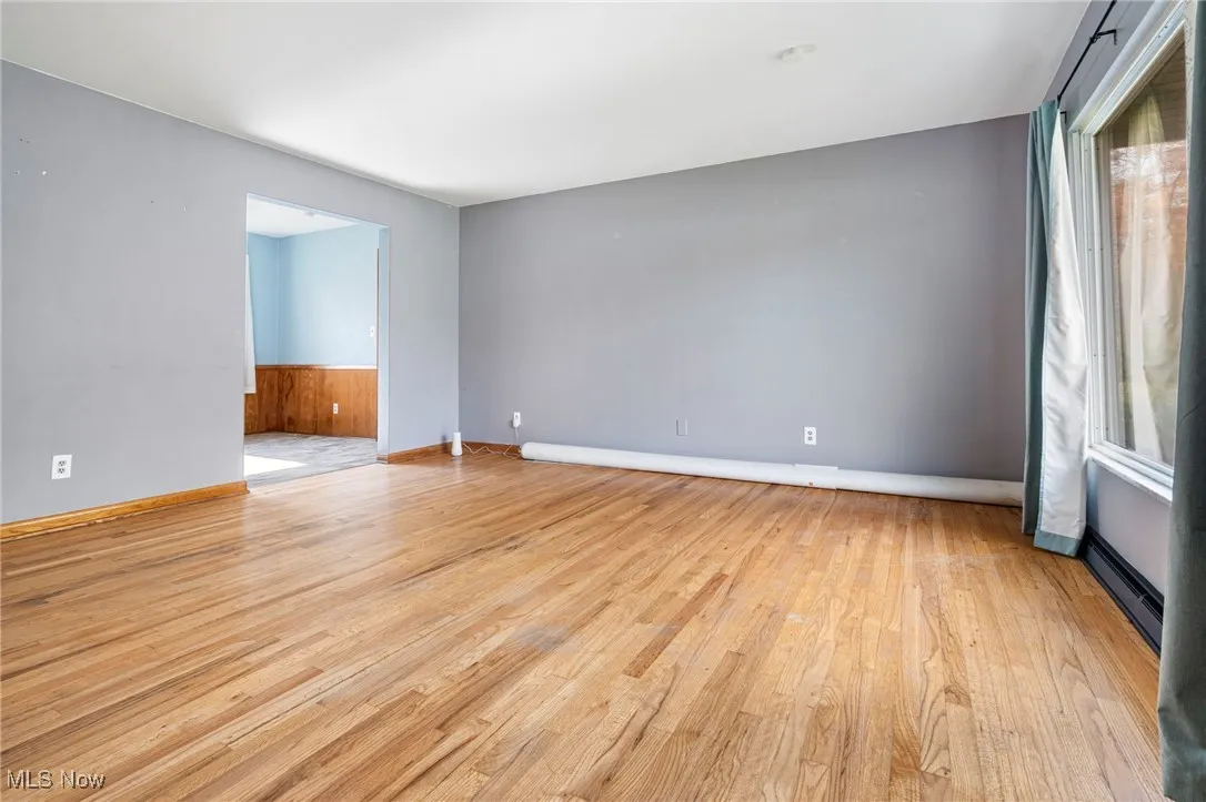 Empty room featuring light wood finished floors and baseboard heating