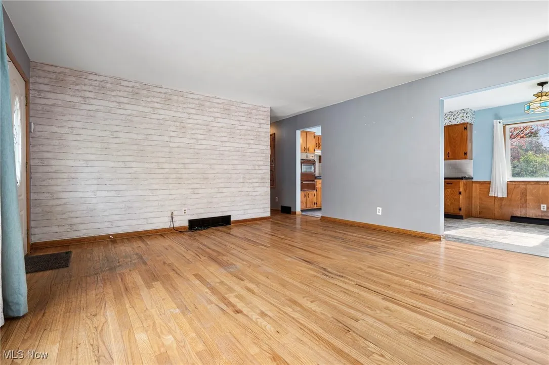 Unfurnished living room with light wood-style floors and wood walls