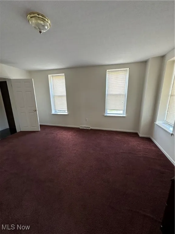 Spare room featuring dark colored carpet and a textured ceiling