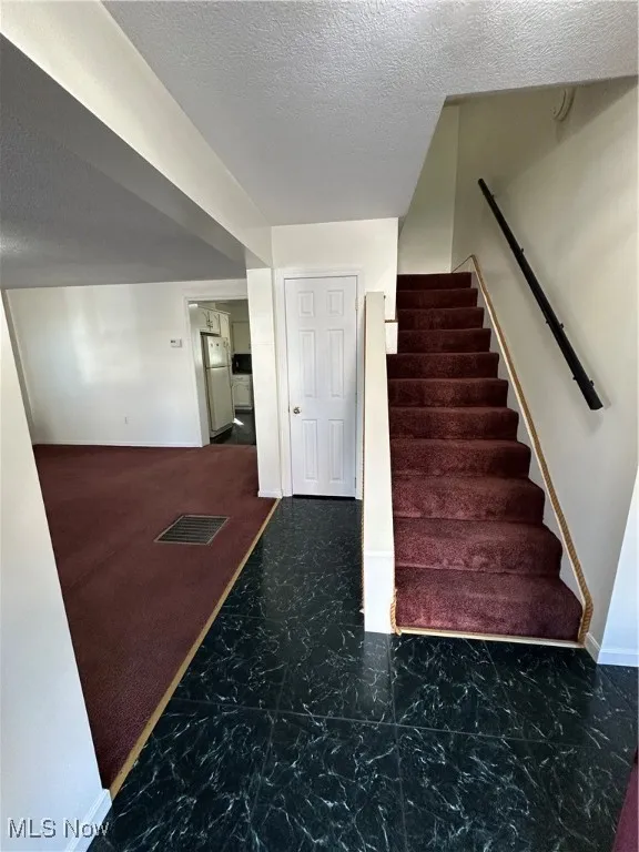 Stairs with a textured ceiling and baseboards