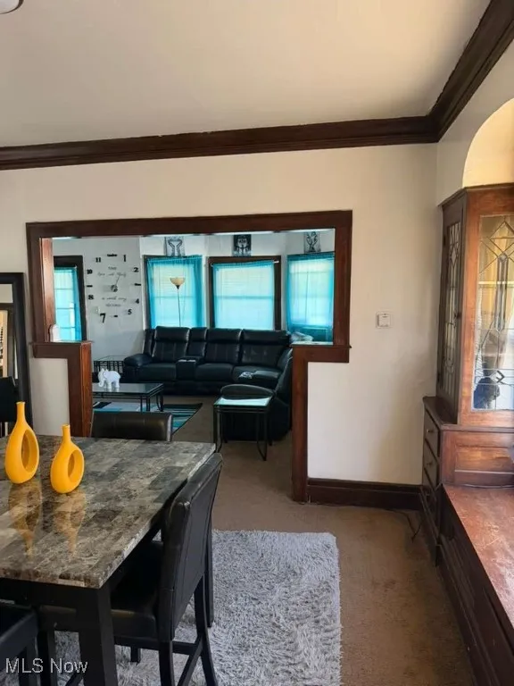Dining room featuring crown molding, light colored carpet, and arched walkways
