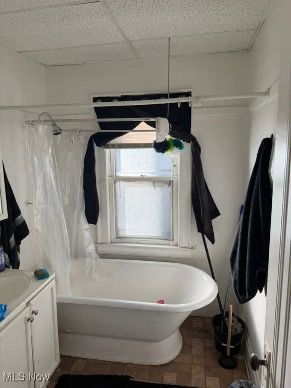 Bathroom featuring shower / bath combo with shower curtain, vanity, and a drop ceiling
