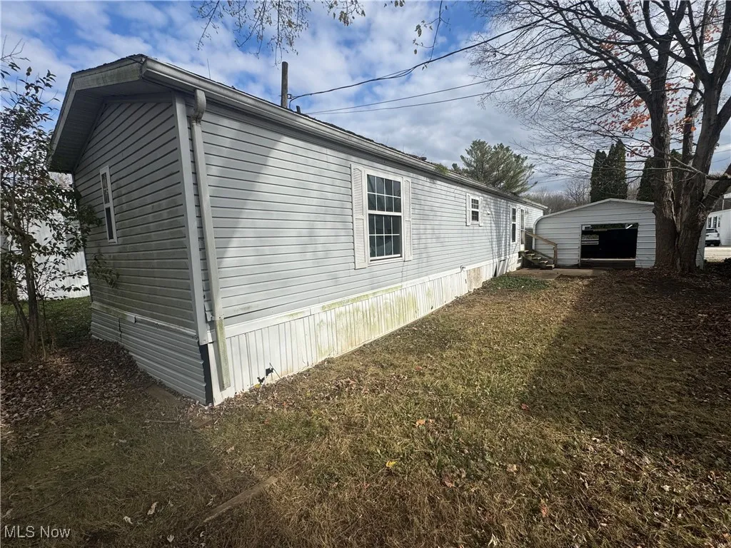 View of property exterior featuring an outbuilding, a detached garage, and a yard