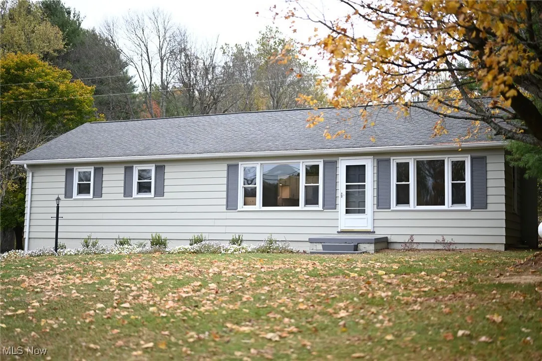 View of front of property with a front yard, roof with shingles, and entry steps