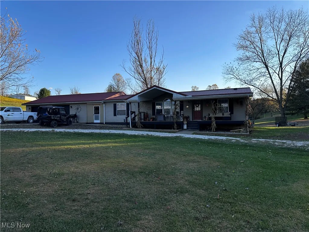 Ranch-style house featuring covered porch and a front lawn
