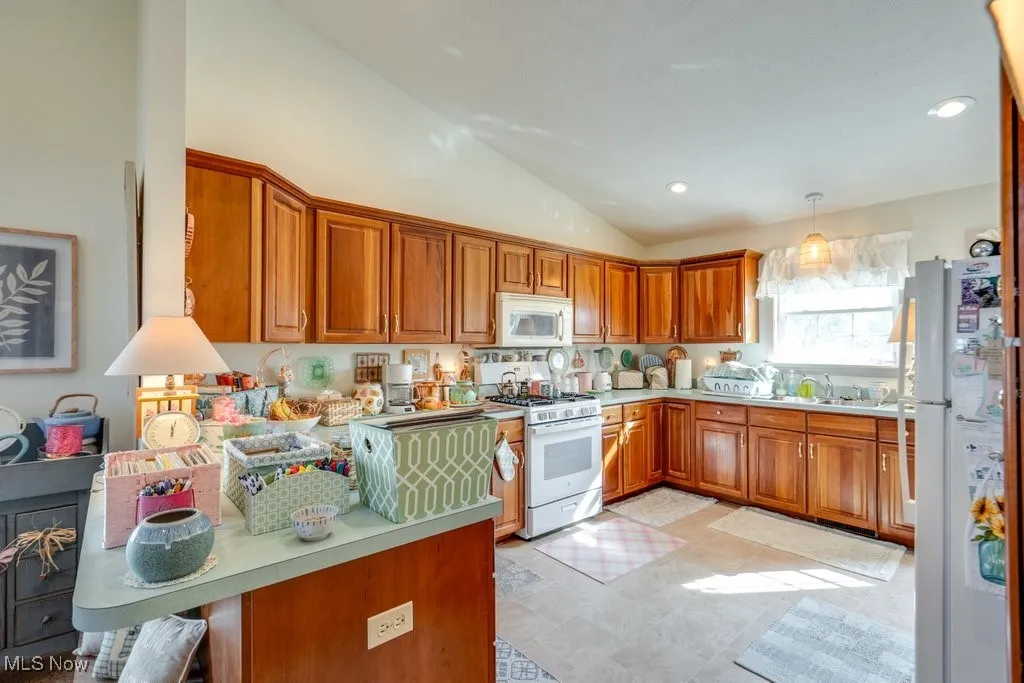 Kitchen with vaulted ceilings, breakfast bar, recessed lighting and laminate flooring