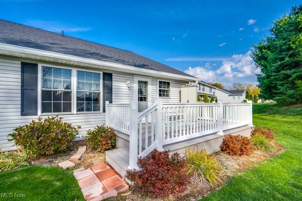 Rear view of house with a wooden deck, a lawn, and roof with shingles