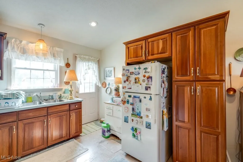 Kitchen with white appliances, lofted ceiling, Cherry cabinets, light countertops, and pendant lighting