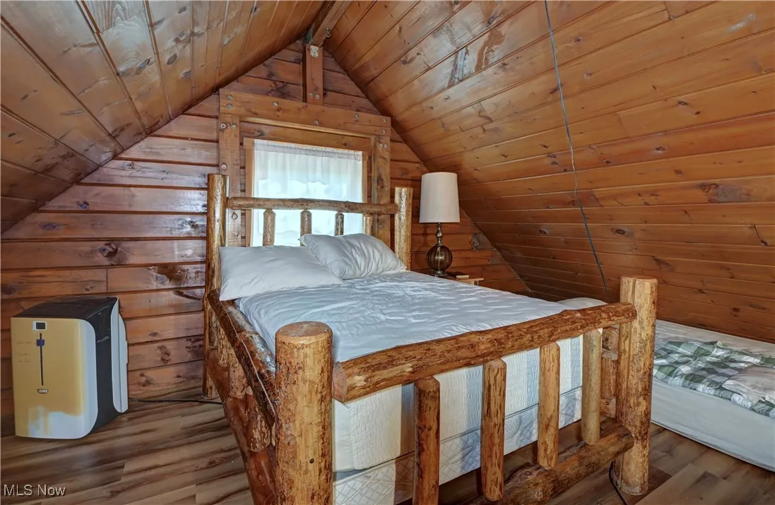 Bedroom with wood walls, wood finished floors, wood ceiling, and vaulted ceiling