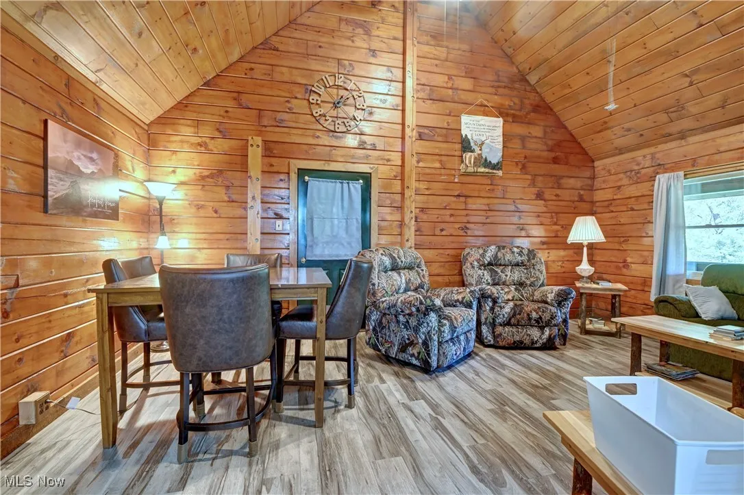 Dining space featuring wooden walls, wood finished floors, high vaulted ceiling, and wooden ceiling
