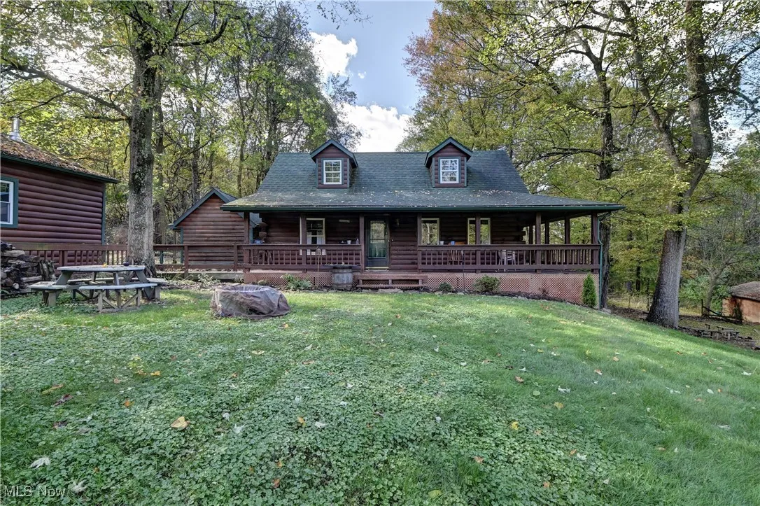 View of front of property featuring covered porch, a front yard, and log exterior