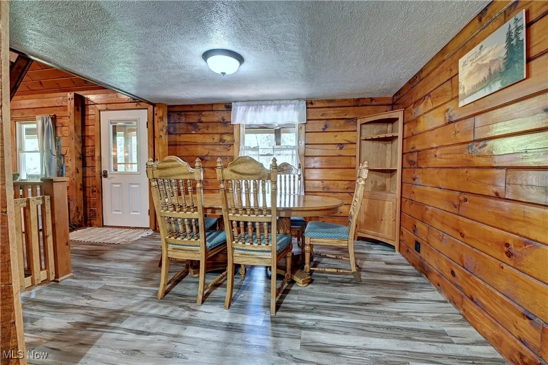 Dining room with wood walls, wood finished floors, and a textured ceiling