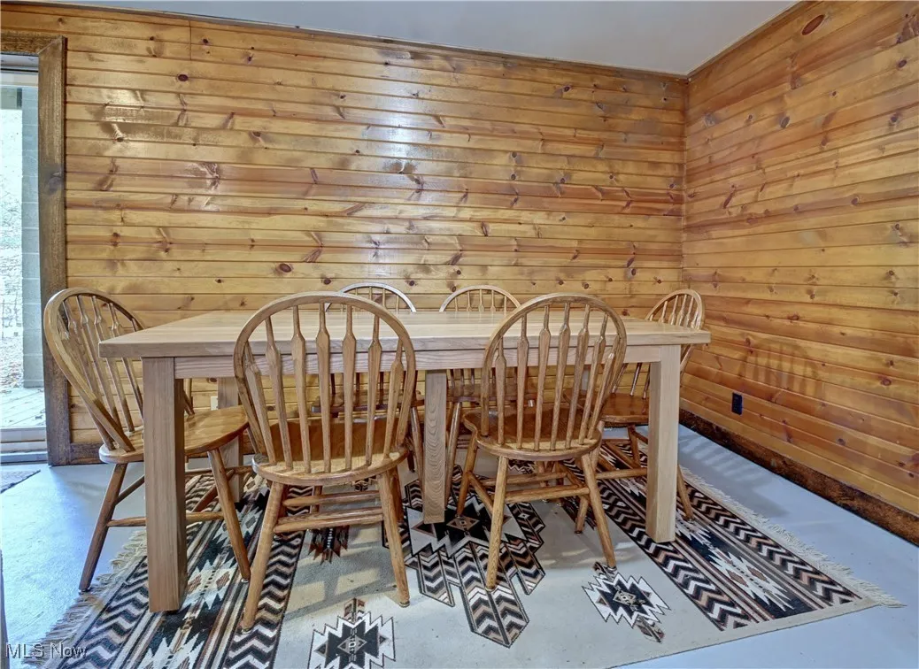 Dining space featuring wooden walls and concrete flooring
