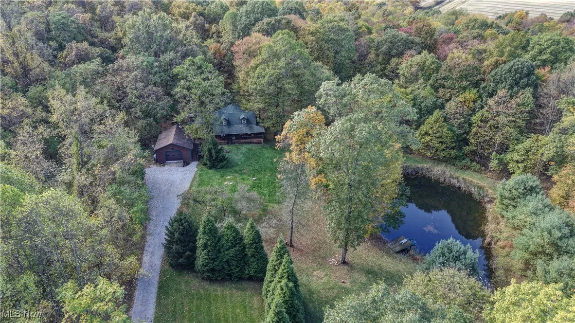Aerial view of property's location featuring a large body of water and a forest