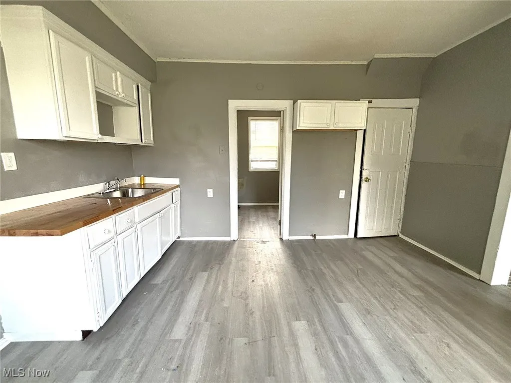 Kitchen with white cabinets, wooden counters, light wood-style floors, and crown molding