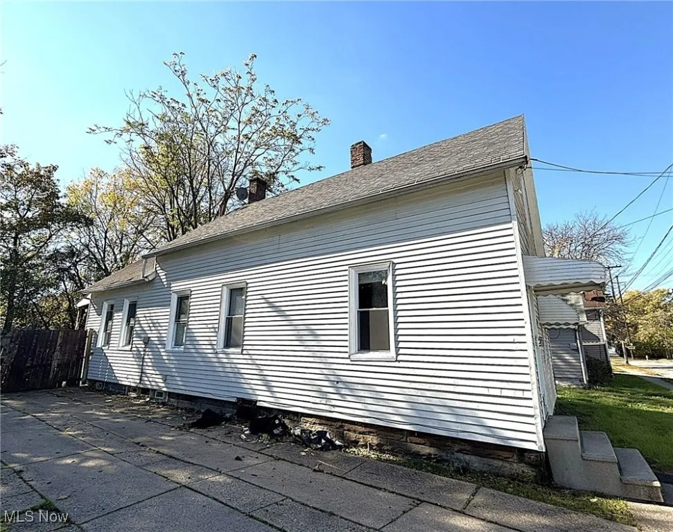 View of side of property with a chimney and roof with shingles