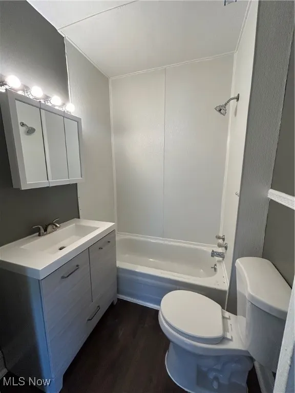 Bathroom featuring dark wood-style flooring, vanity, and washtub / shower combination
