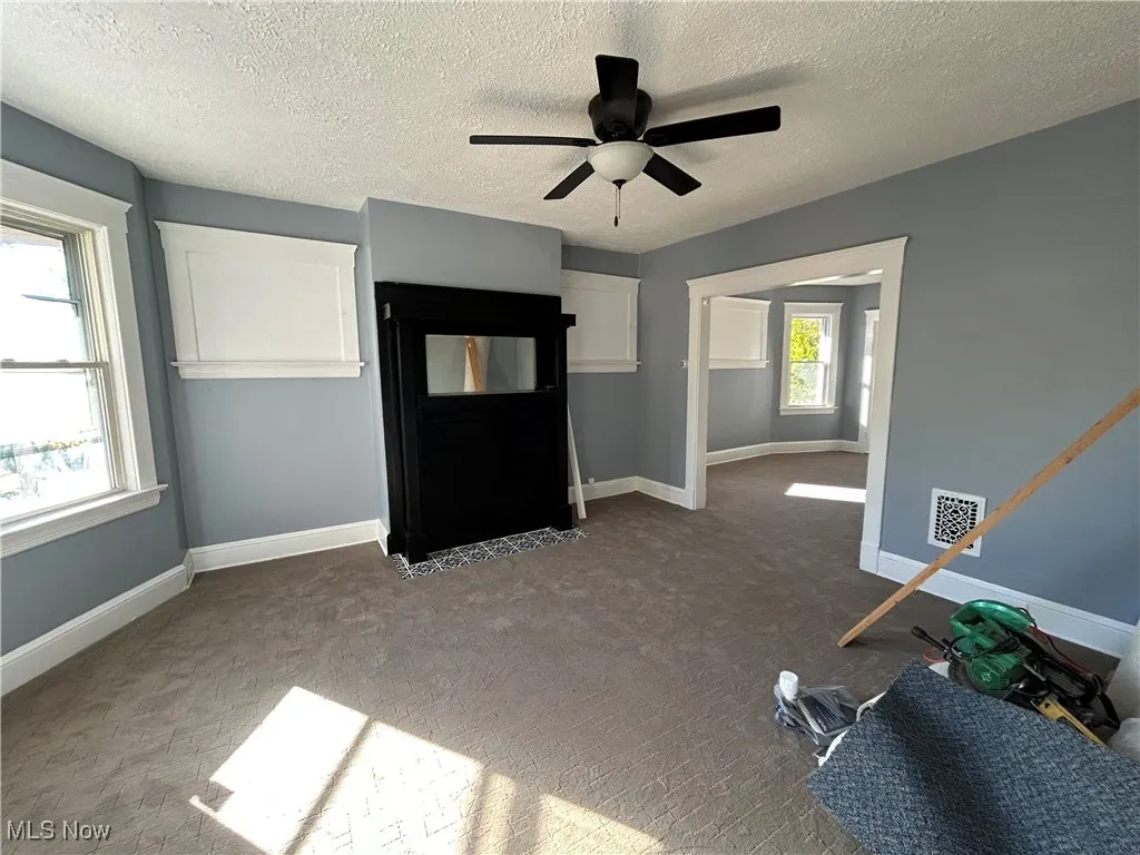 Unfurnished living room with carpet, a textured ceiling, and a ceiling fan