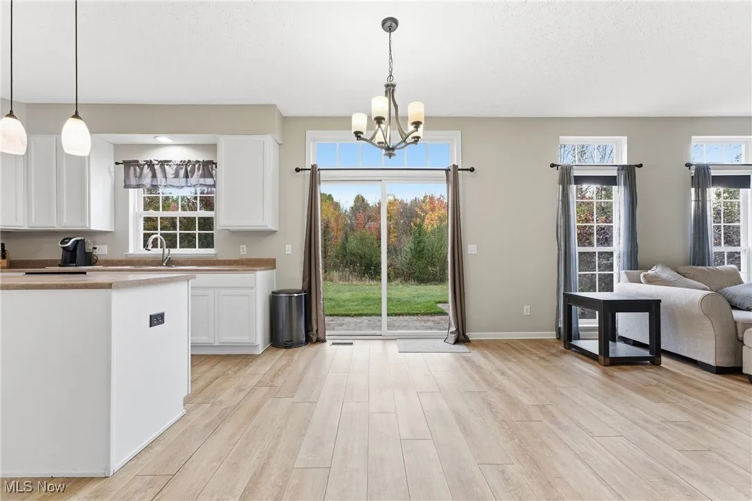 Kitchen featuring a chandelier, light wood-style flooring, open floor plan, white cabinets, and hanging light fixtures