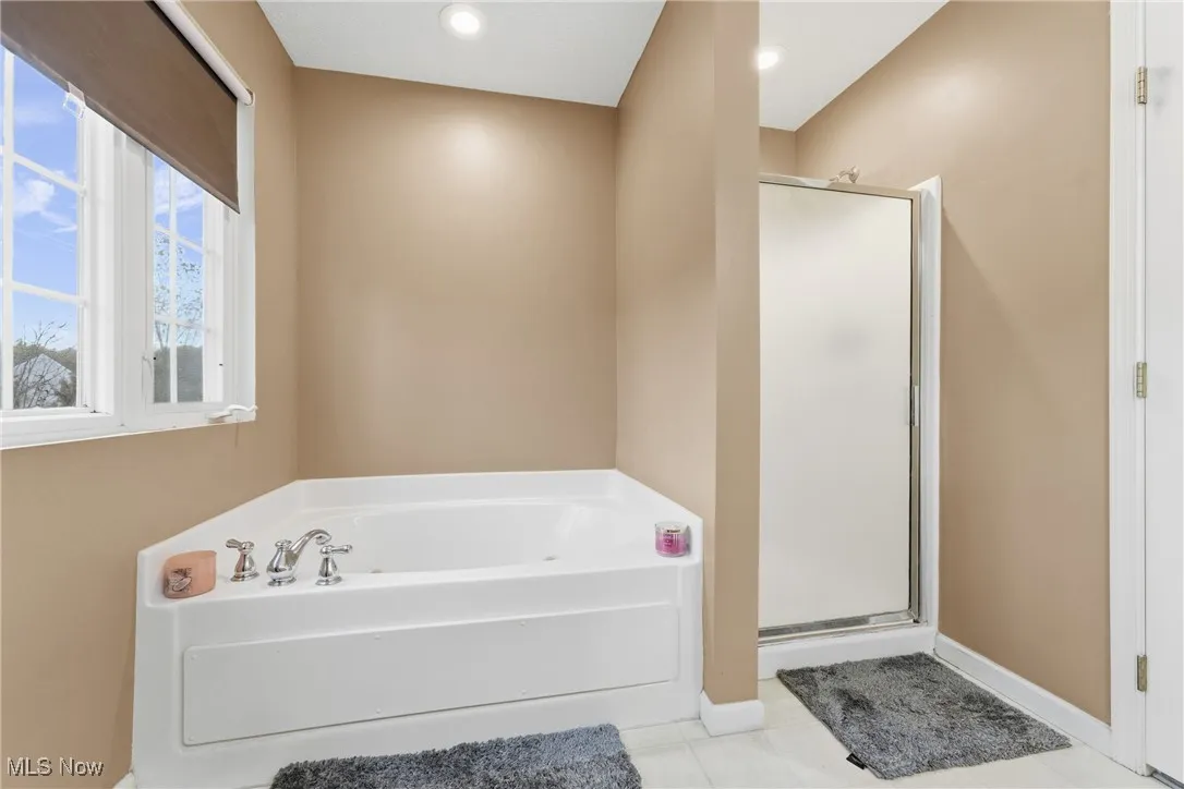 Full bathroom featuring a bath, light tile patterned floors, and a shower stall