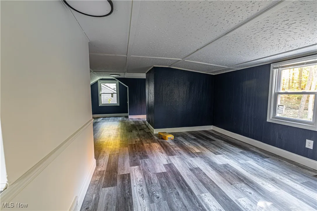 Spare room featuring wood finished floors, wooden walls, and a decorative wall