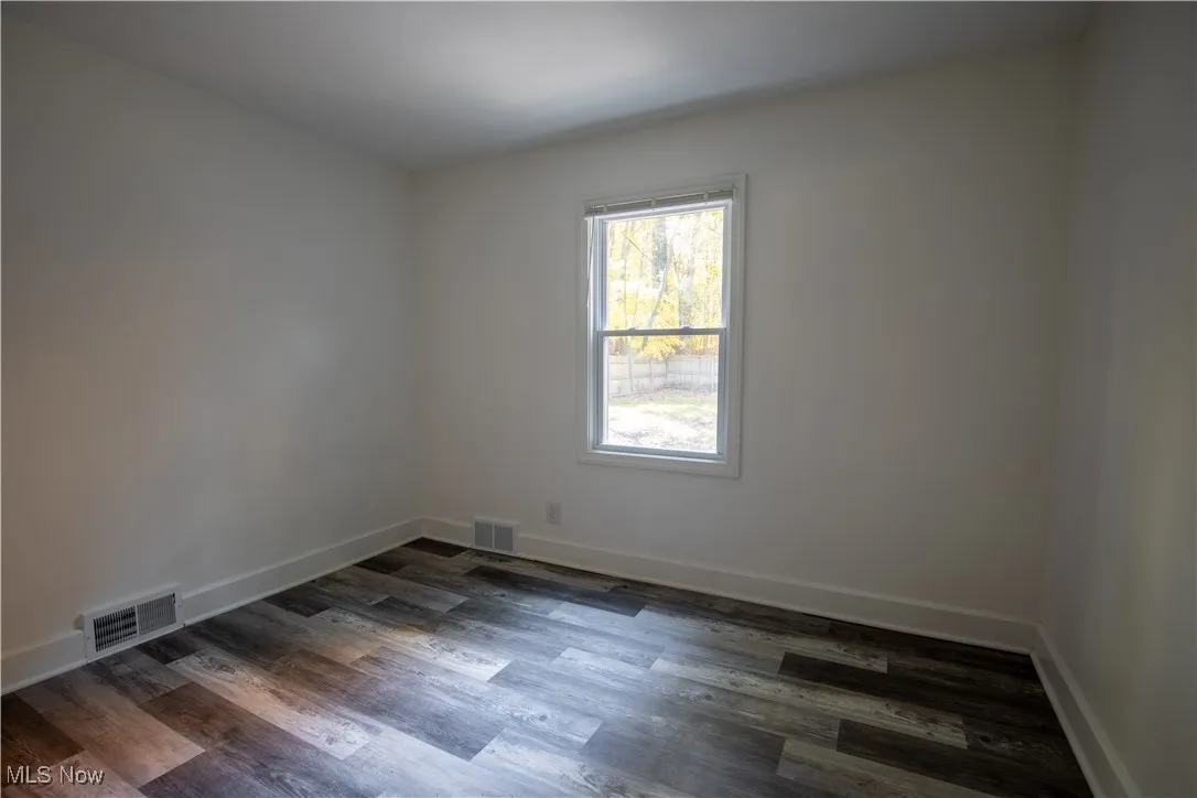 Unfurnished room featuring baseboards and dark wood-type flooring