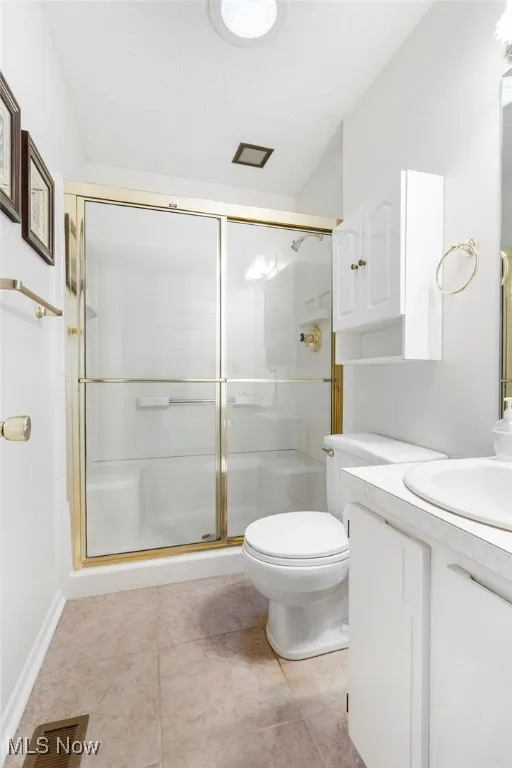 Bathroom with vanity, light tile patterned flooring, a textured ceiling, and a stall shower
