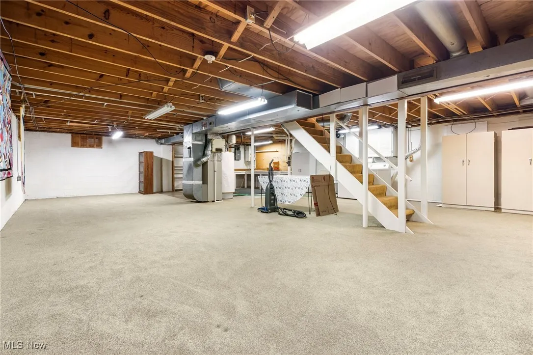 Below grade area featuring stairway, heating unit, water heater, and carpet