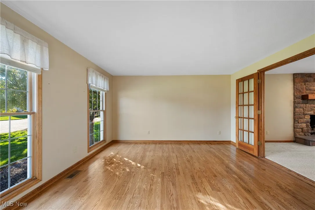 Light streams through large oversized windows in this living room.  Glass paned french doors open to family room giving the room versatility as a home office.