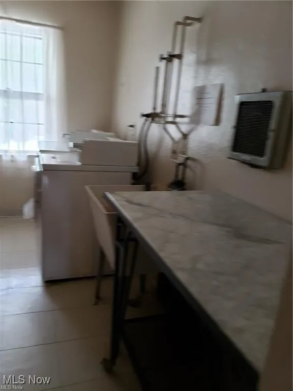 Washroom with washer / clothes dryer and light tile patterned floors