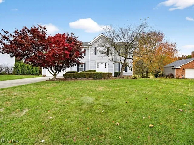 View of front of house with a front lawn, a garage, and concrete driveway