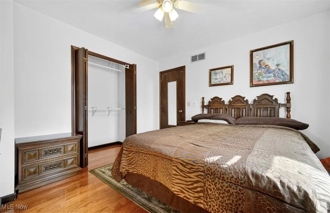 Bedroom with a closet, light wood finished floors, and a ceiling fan