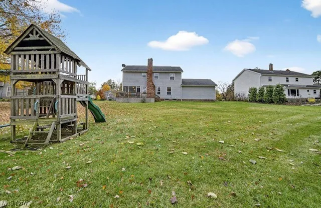 Back of property with a yard, a playground, and a chimney