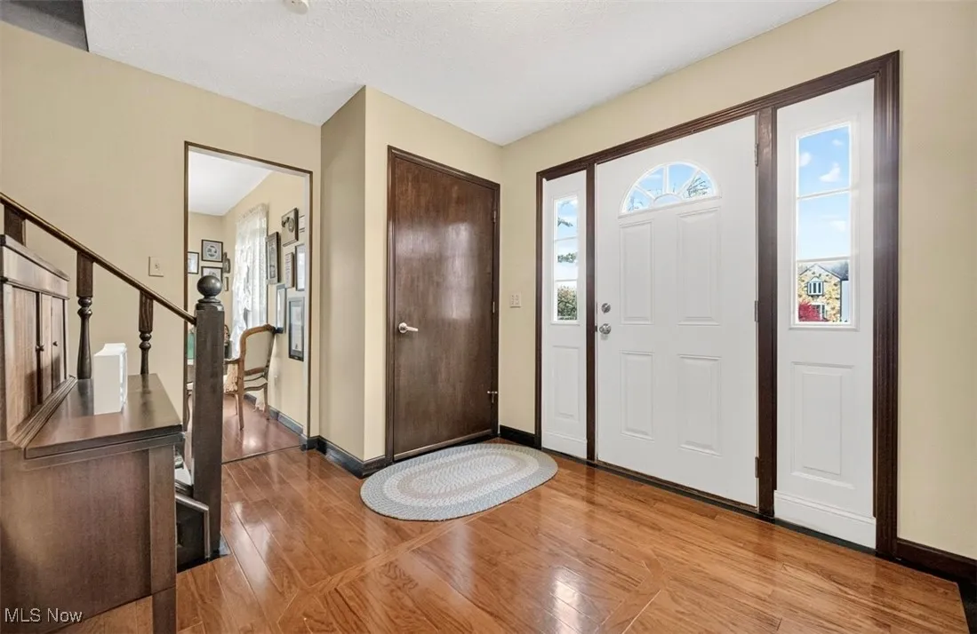 Entryway featuring light wood finished floors, stairs, and a textured ceiling