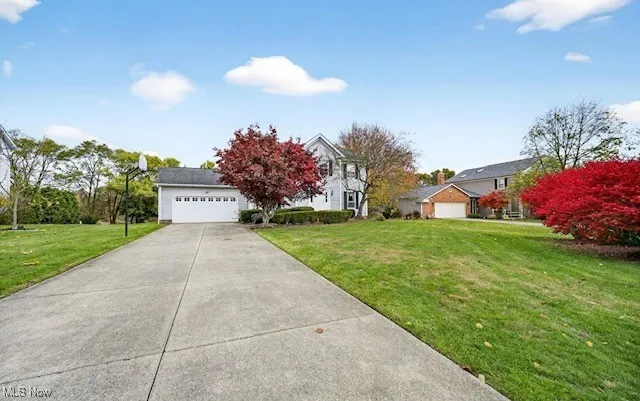View of front of property with a garage, a front lawn, and concrete driveway