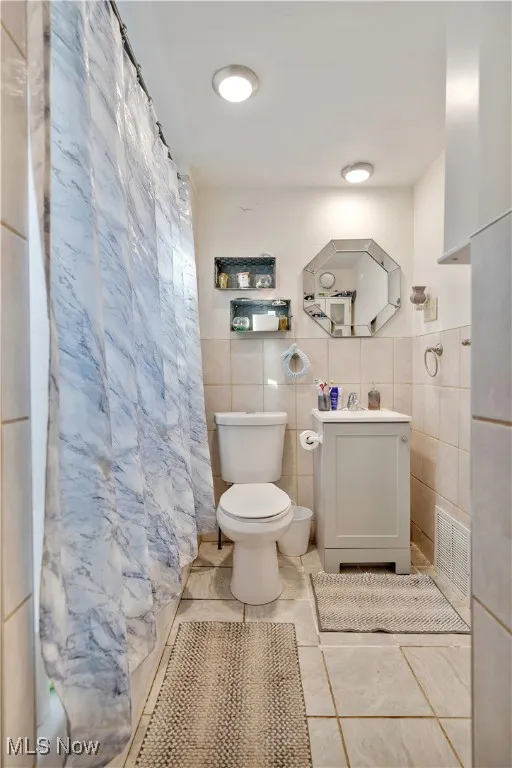 Bathroom with tile walls, vanity, a shower with curtain, and tile patterned floors