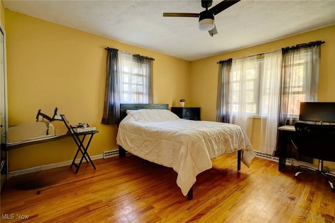 Bedroom with light wood-type flooring, a ceiling fan, a textured ceiling, and a desk