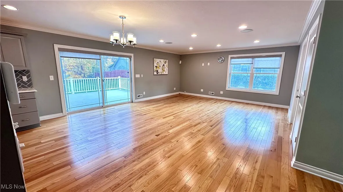 Empty room featuring recessed lighting, light wood-type flooring, crown molding, and a chandelier