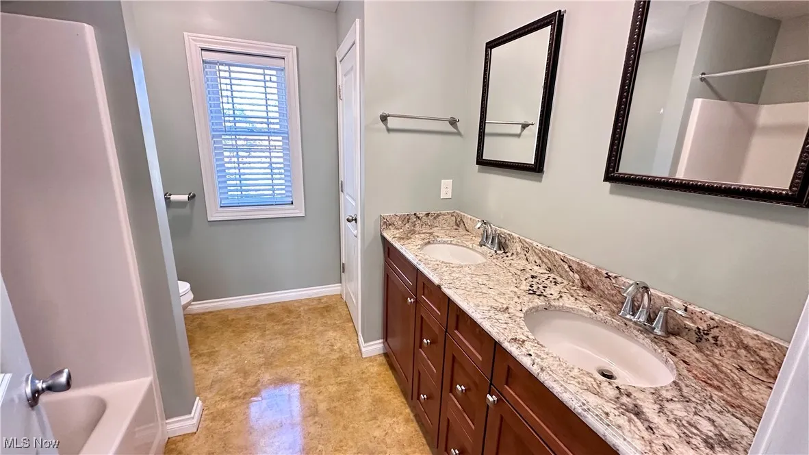 Full bath with double vanity and baseboards