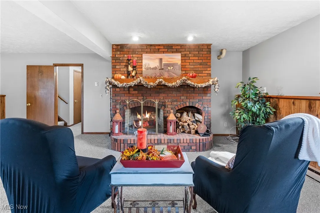 Living room with a fireplace, carpet flooring, and a textured ceiling