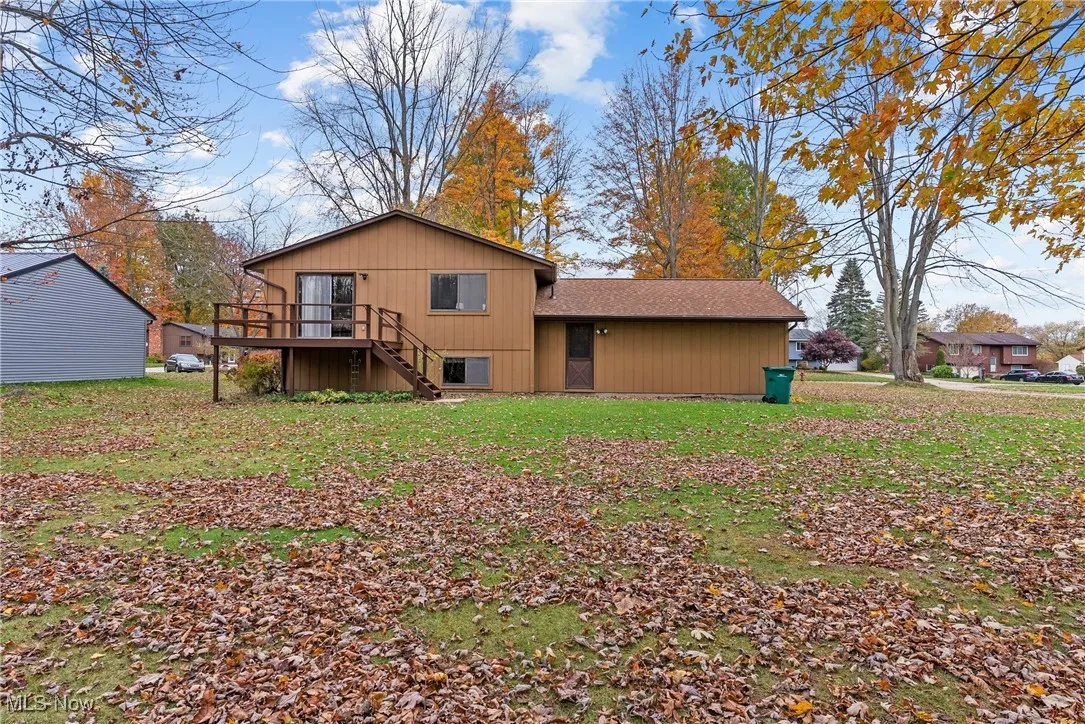 Back of house featuring stairs, a wooden deck, and a yard