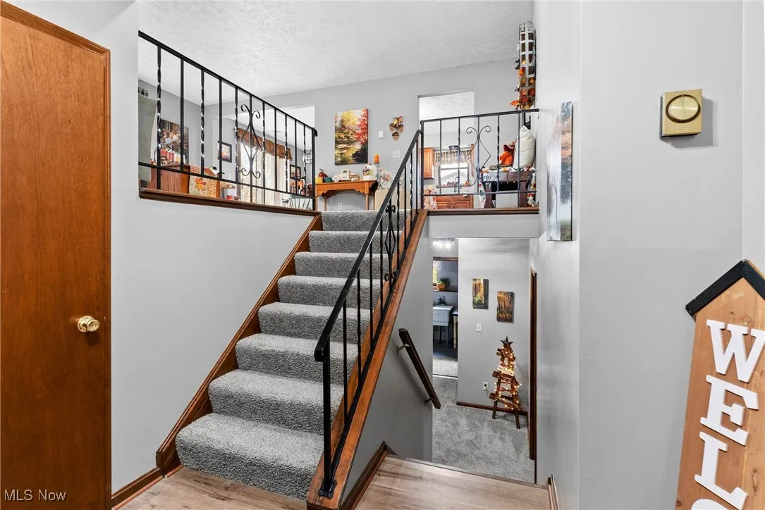 Staircase featuring wood finished floors, a towering ceiling, and a textured ceiling