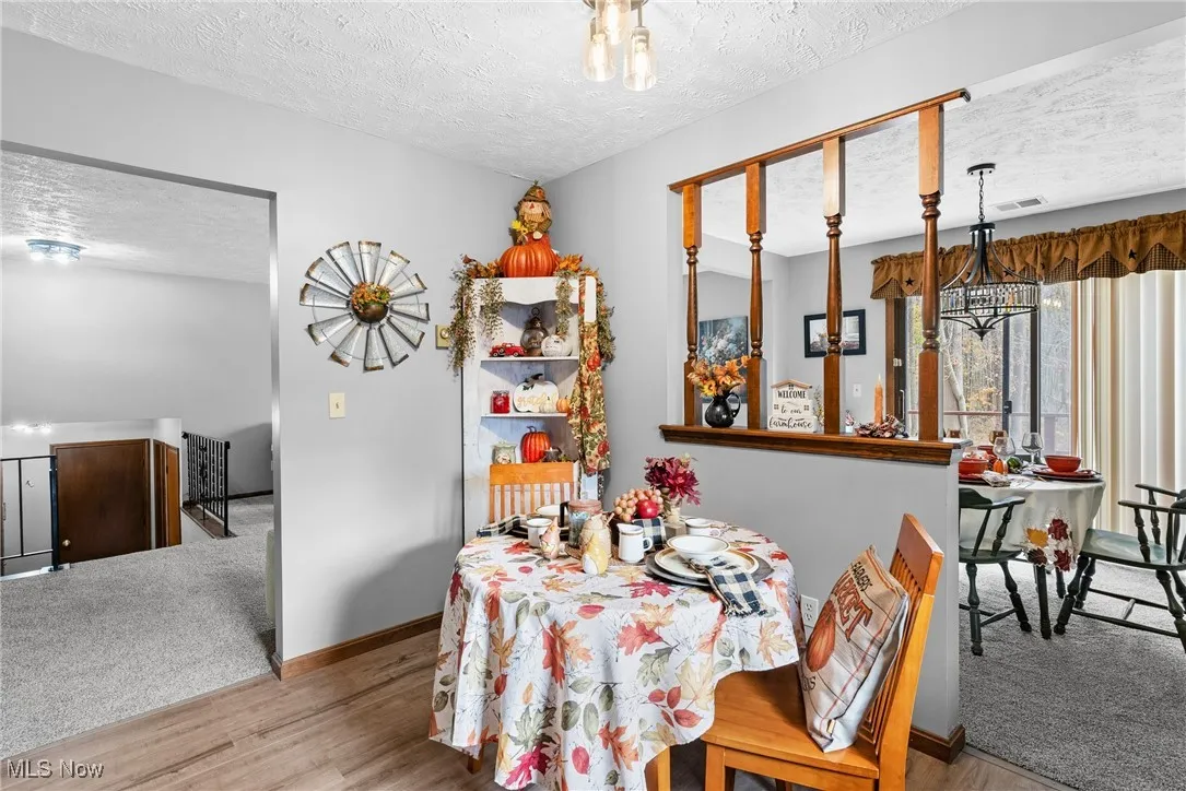 Dining area featuring a textured ceiling, a chandelier, carpet flooring, and wood finished floors