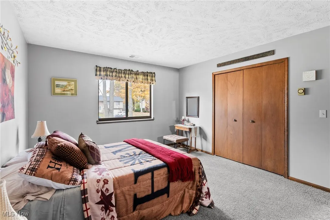 Carpeted bedroom with a closet and a textured ceiling