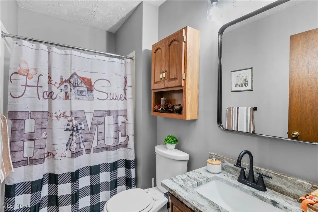 Full bath featuring a textured ceiling, a shower with curtain, and vanity