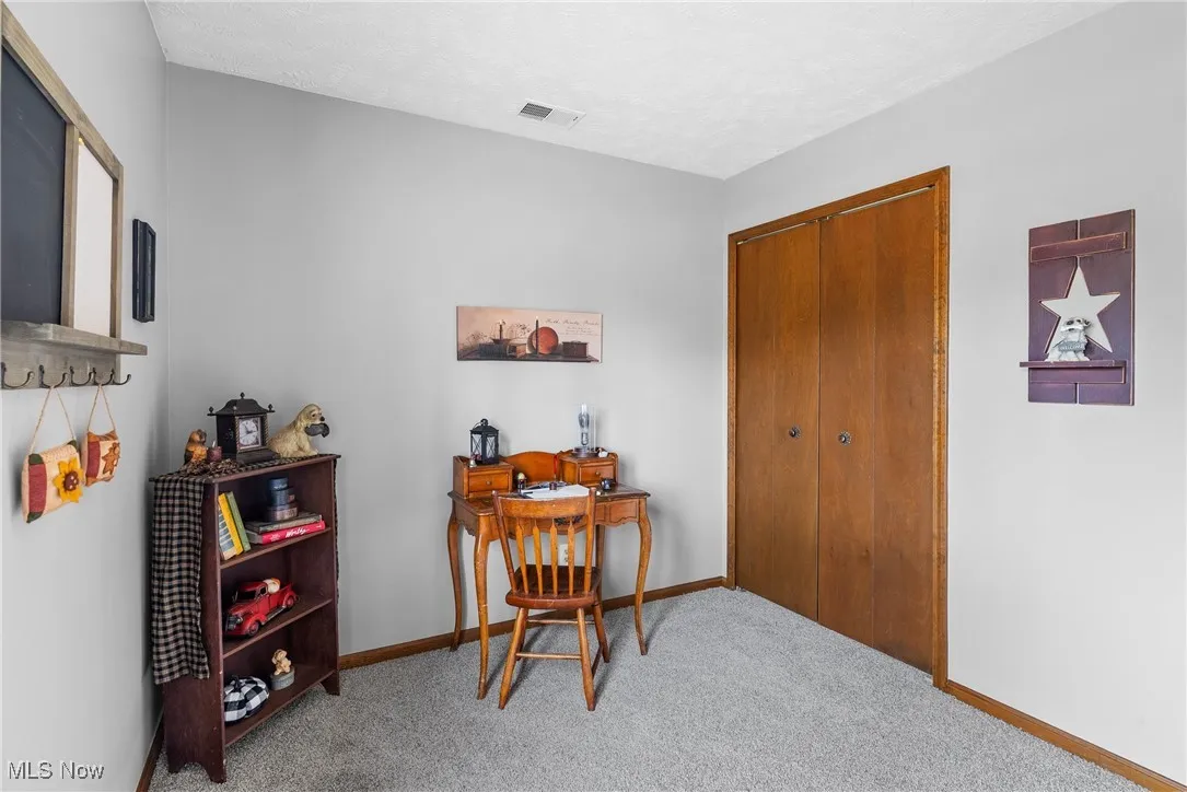 Carpeted home office with a textured ceiling