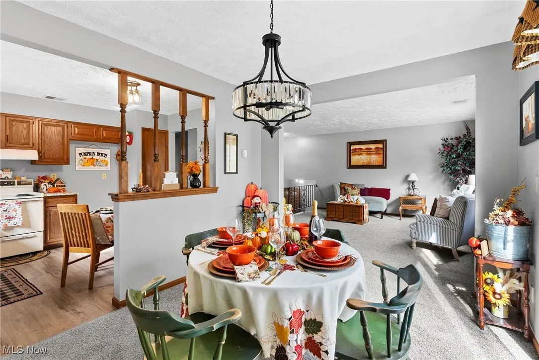 Carpeted dining area with a textured ceiling and a chandelier
