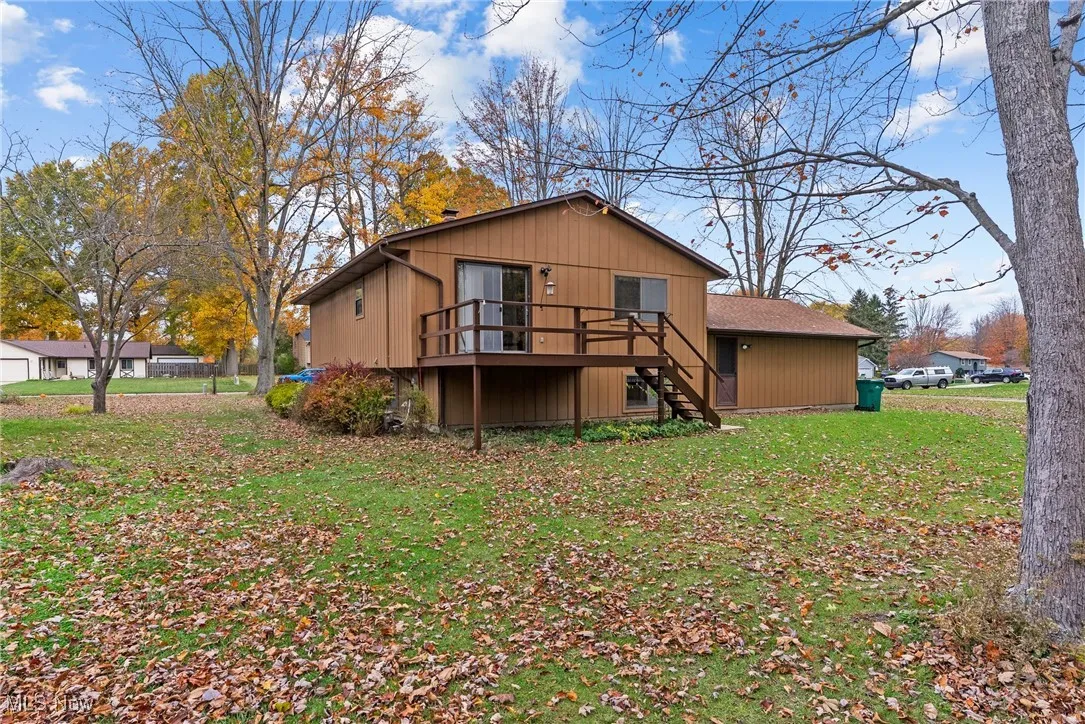 Rear view of property with stairway, a yard, and a wooden deck
