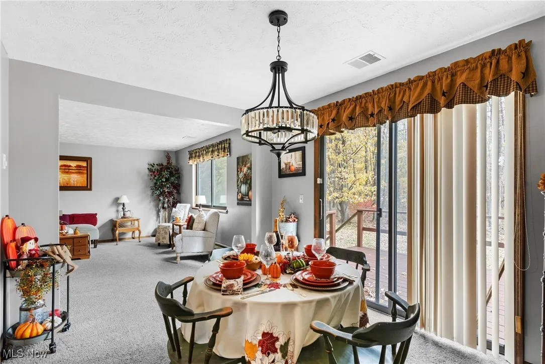 Dining room with a textured ceiling, carpet floors, and a chandelier